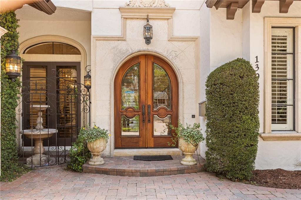 An arched wooden double door serves as the entrance to a home with stone accents — 1398 GROVE TERRACE, WINTER PARK, FL