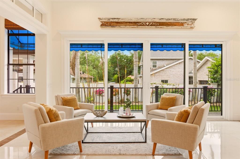 A living room features four beige armchairs around a coffee table before large glass doors — 1398 GROVE TERRACE, WINTER PARK, FL