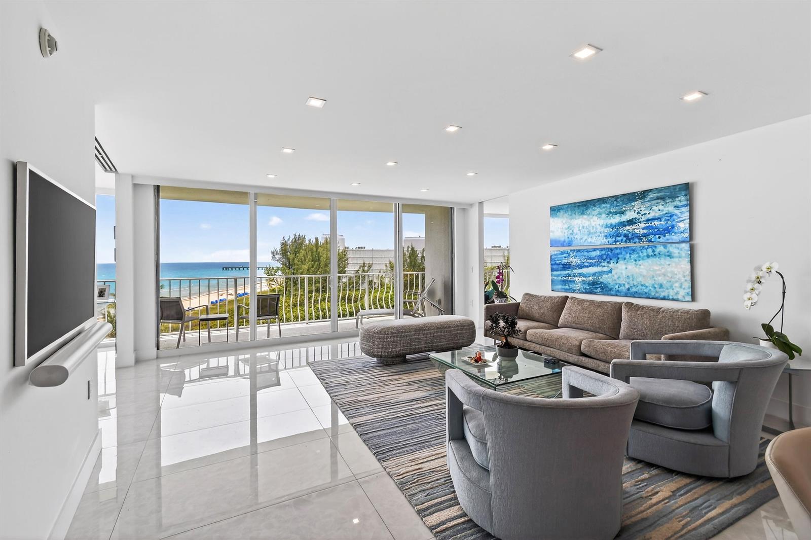 A modern living room features white tile floors, a large sectional, and floor-to-ceiling ocean views — 2774 S Ocean Boulevard # 704, Palm Beach FL 33480, PALM BEACH, FL