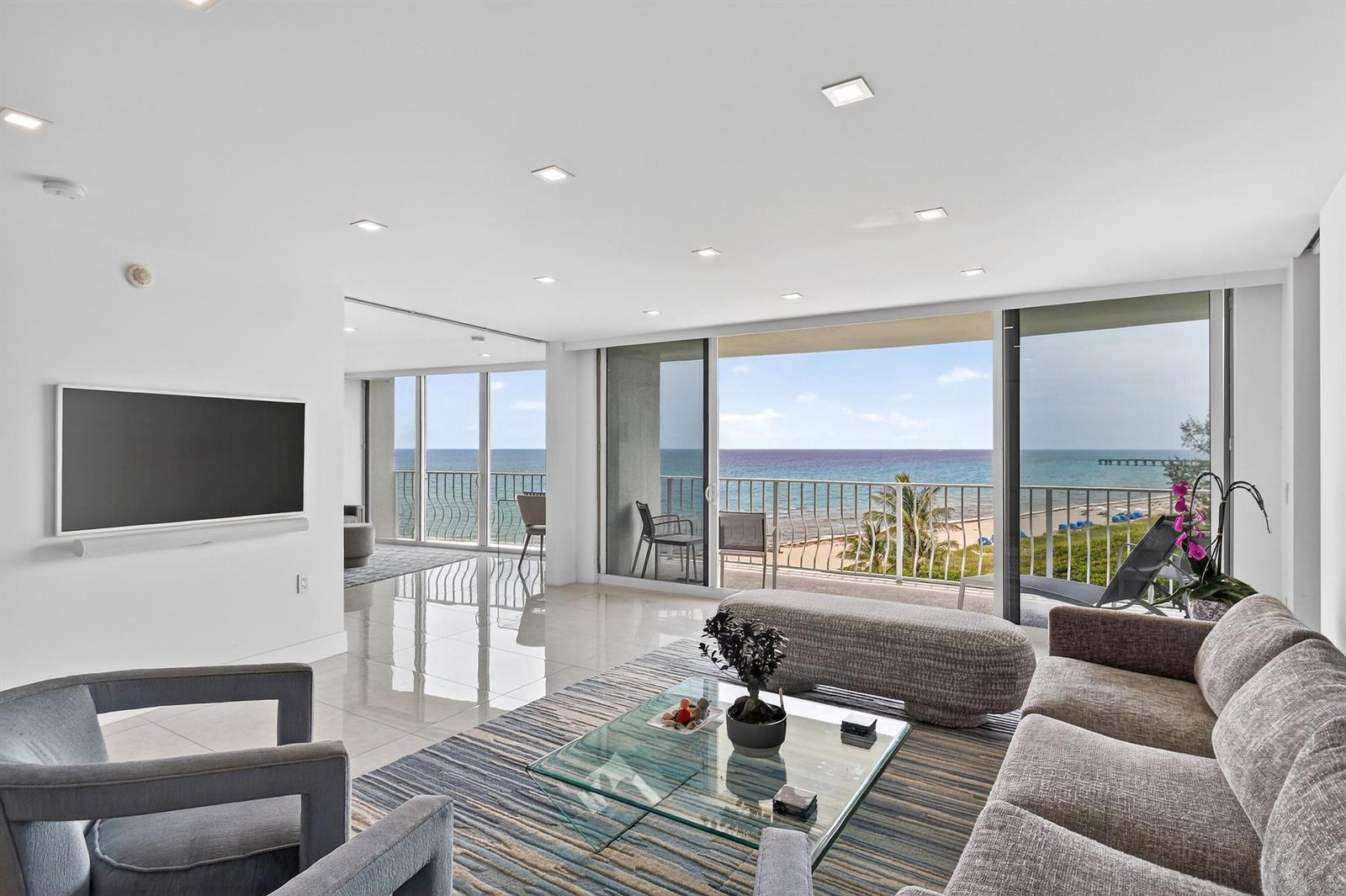 A living room with tile floors, a glass coffee table, and sliding doors to a balcony — 2774 S Ocean Boulevard # 704, Palm Beach FL 33480, PALM BEACH, FL