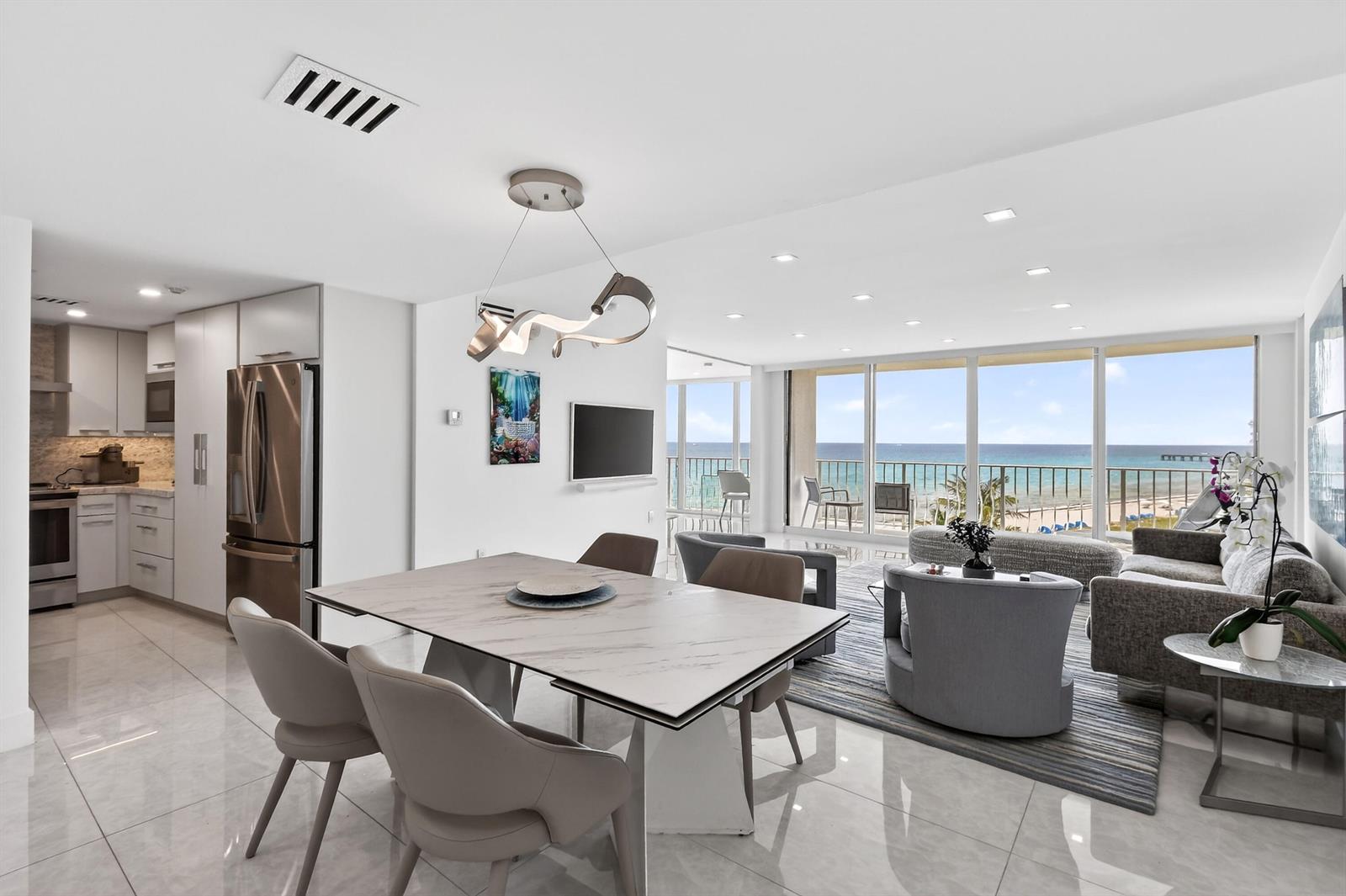 An open-concept living and dining area features marble floors, modern lighting, and oceanfront balcony views — 2774 S Ocean Boulevard # 704, Palm Beach FL 33480, PALM BEACH, FL