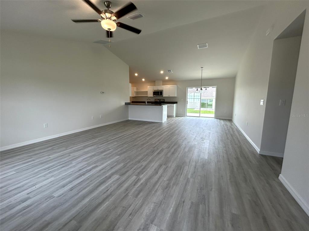 An open-concept living area features light gray wood-look flooring and a kitchen with white cabinetry — 8309 N INDIA WAY, CITRUS SPRINGS, FL