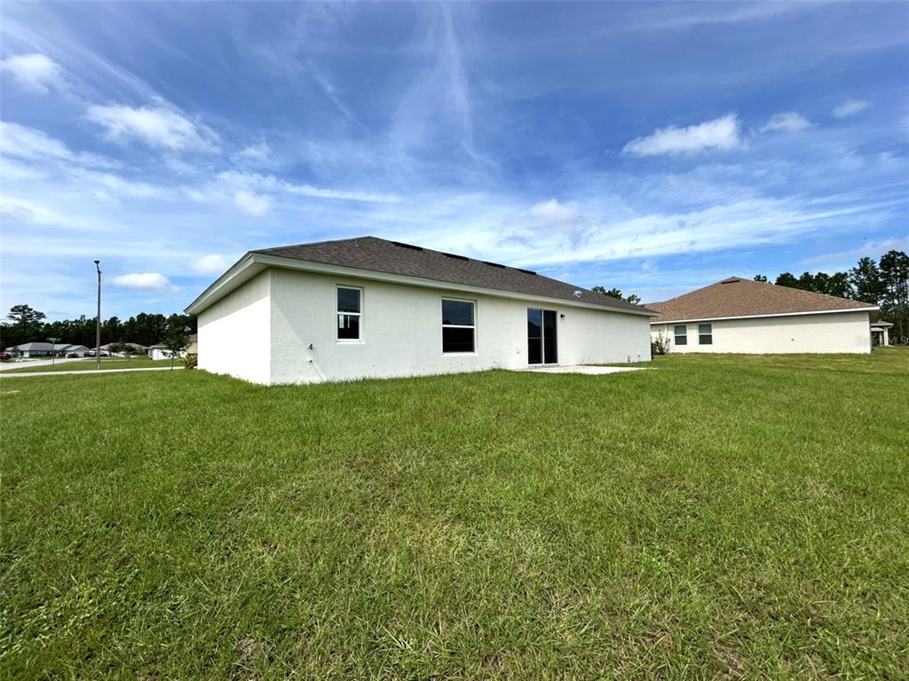 The exterior rear view of a white single-story house with a lawn and sliding doors — 8309 N INDIA WAY, CITRUS SPRINGS, FL