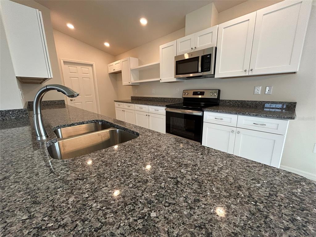 A kitchen features white cabinets, granite countertops, a stainless steel sink, and stainless steel appliances — 8309 N INDIA WAY, CITRUS SPRINGS, FL
