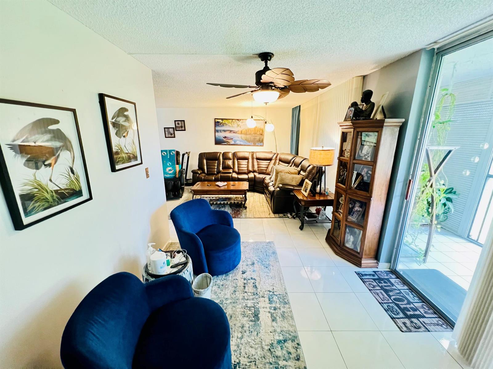 A living room features blue velvet chairs, a brown sectional, and a wooden display cabinet — 3821 Environ Boulevard # 203, Lauderhill FL 33319, LAUDERHILL, FL