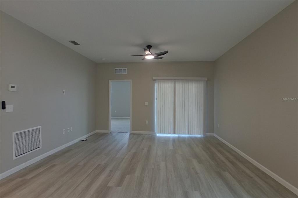 A living room with light wood-look flooring, a ceiling fan, and sliding glass doors — 6376 GREEN BUD DRIVE, GROVELAND, FL