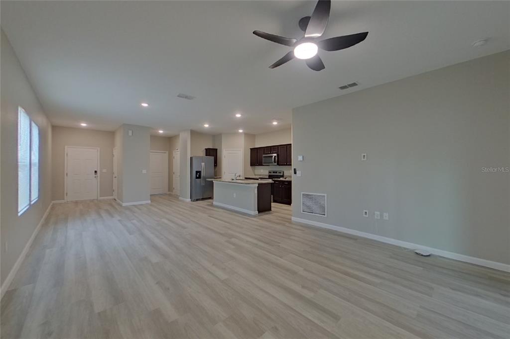 An open-concept living area features light wood-look flooring, a kitchen island, and dark cabinetry — 6376 GREEN BUD DRIVE, GROVELAND, FL