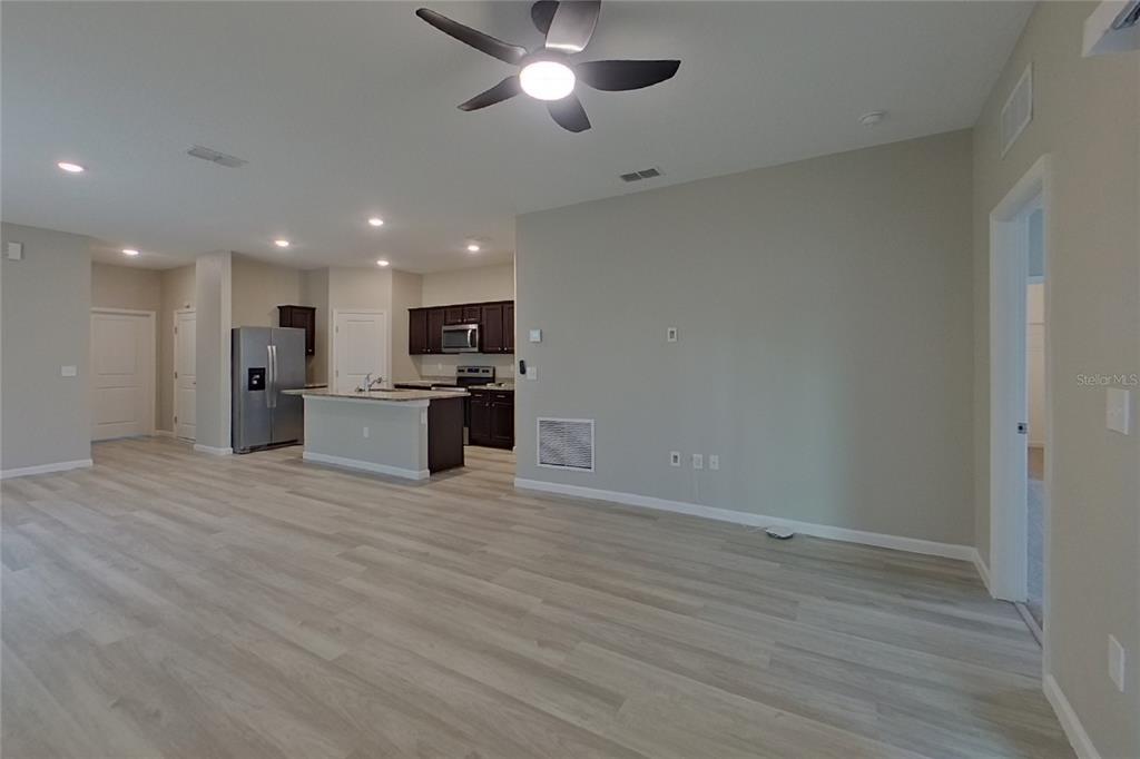 An open-concept living area features light wood-look flooring, a ceiling fan, and a kitchen island — 6376 GREEN BUD DRIVE, GROVELAND, FL
