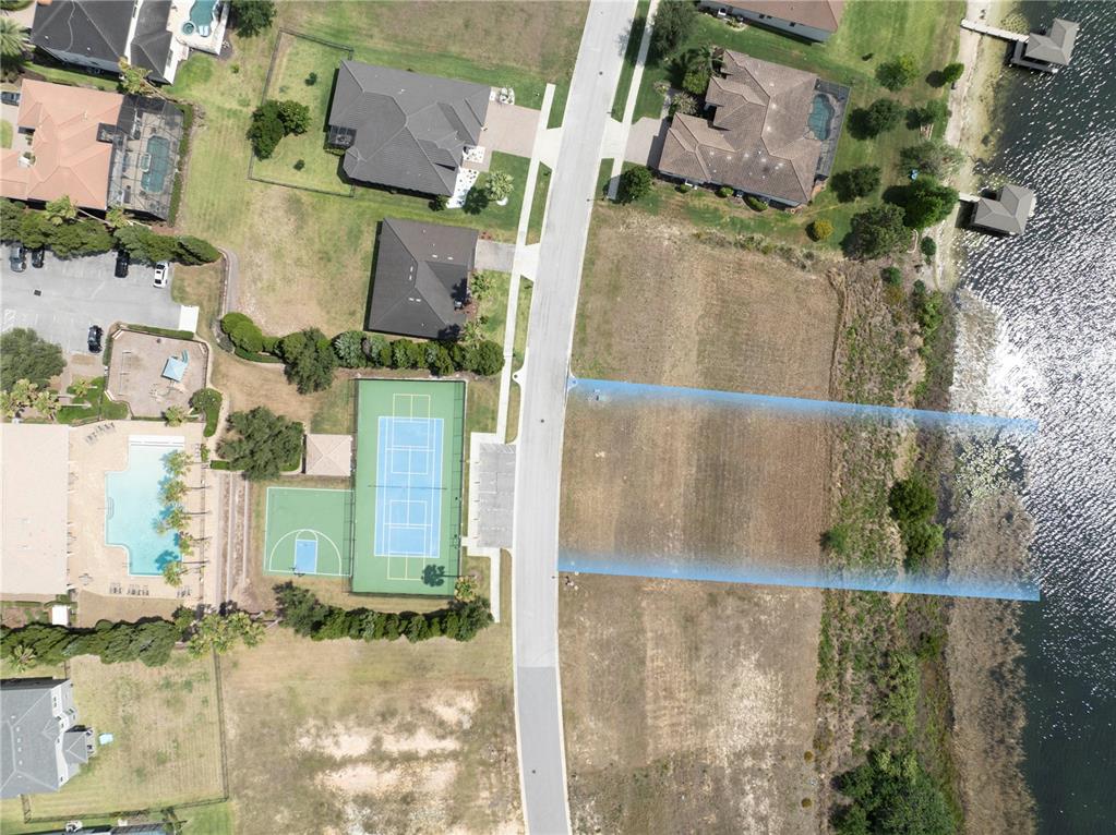 An aerial view shows a vacant waterfront lot highlighted in blue across from a community center — 4253 JULIANA LAKE DRIVE, AUBURNDALE, FL