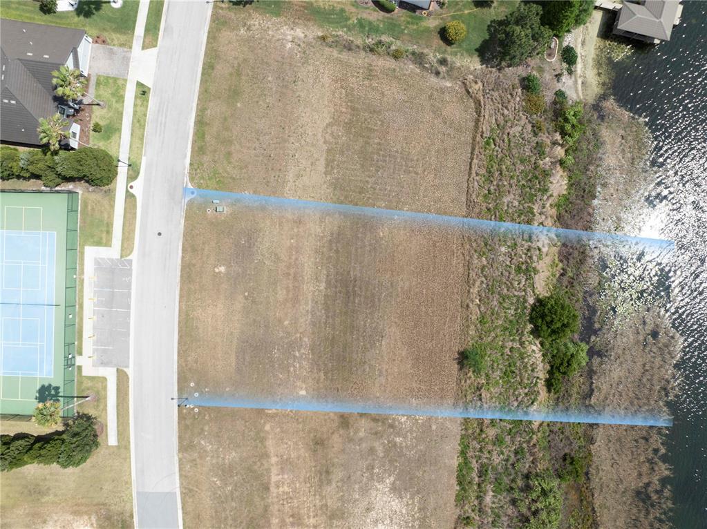 An aerial view shows a vacant, rectangular waterfront lot bordered by a road and vegetation — 4253 JULIANA LAKE DRIVE, AUBURNDALE, FL