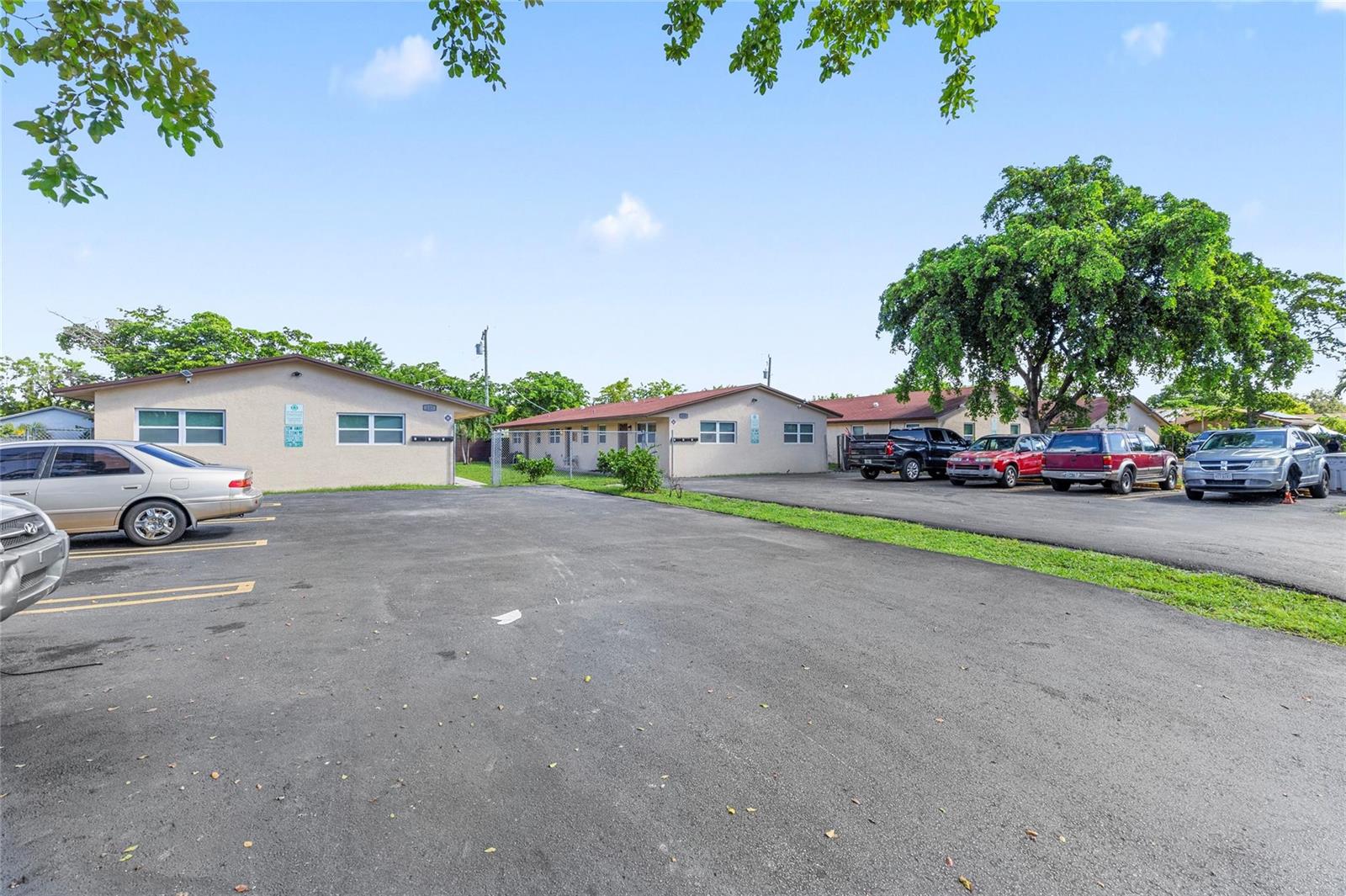 An exterior view of single-story apartment buildings with a paved parking lot in front — 237 NW 12th Court, Pompano Beach FL 33060, POMPANO BEACH, FL