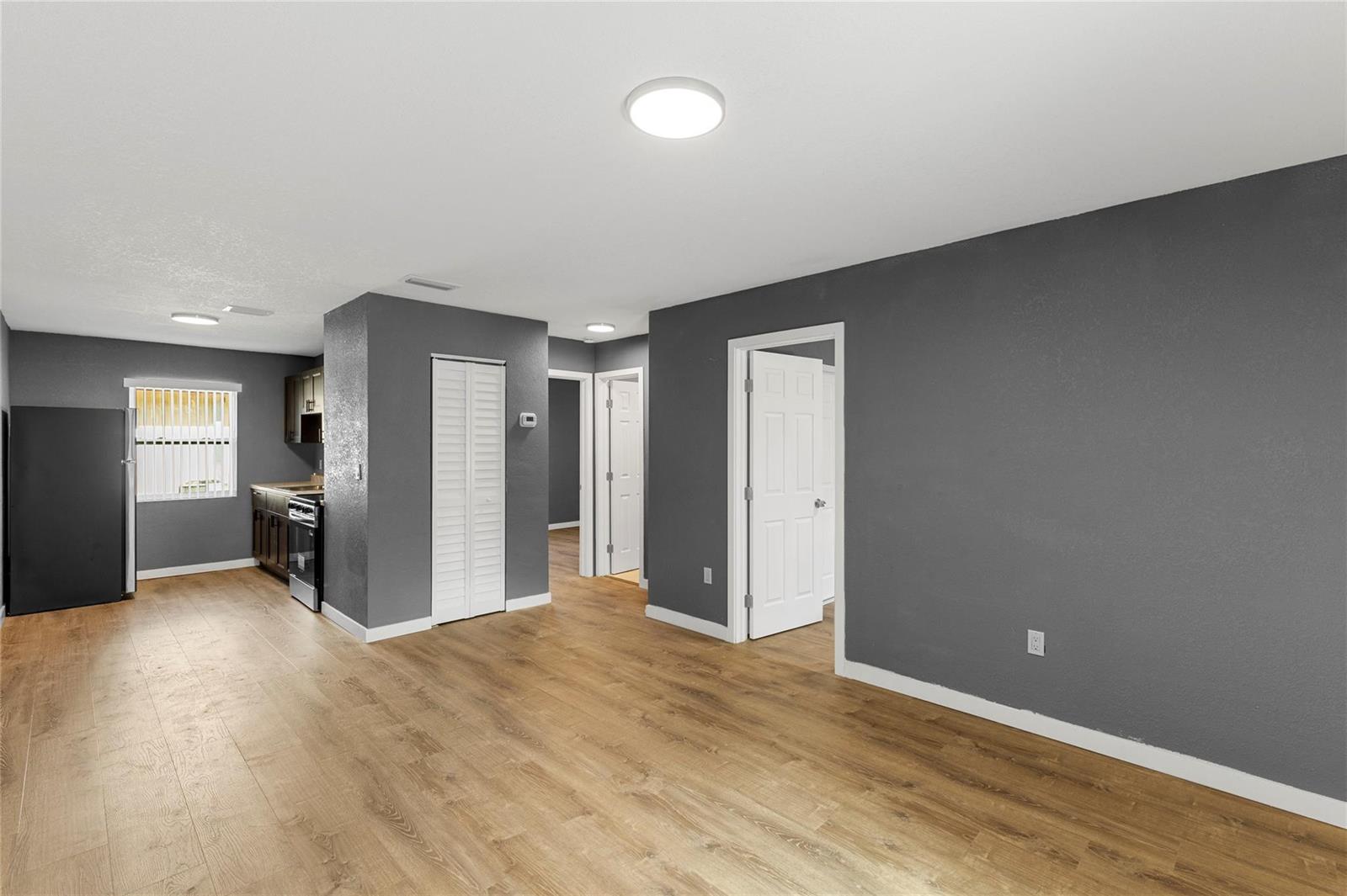 An open-concept living area features gray walls, wood-look flooring, and an adjacent kitchen — 237 NW 12th Court, Pompano Beach FL 33060, POMPANO BEACH, FL