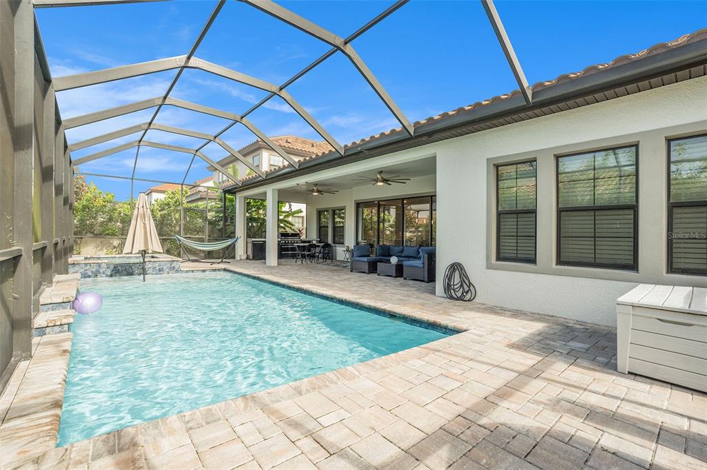 A screened-in patio features a swimming pool, a covered seating area, and paver decking — 21698 AMELIA ROSE WAY WAY, LAND O LAKES, FL