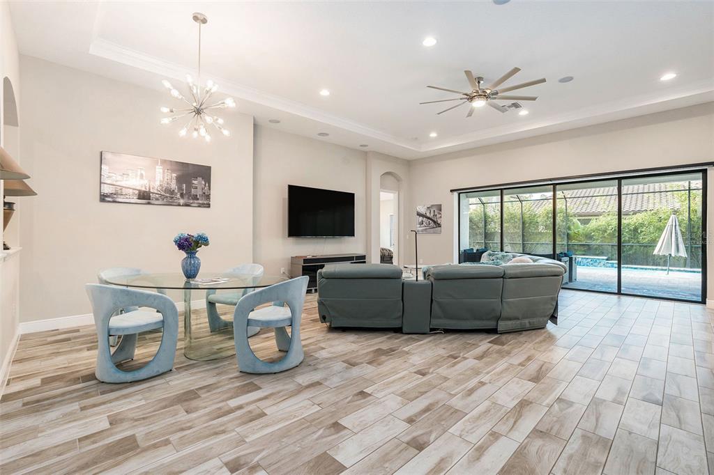 A spacious living and dining area with tile flooring, a glass table, and sliding glass doors — 21698 AMELIA ROSE WAY WAY, LAND O LAKES, FL