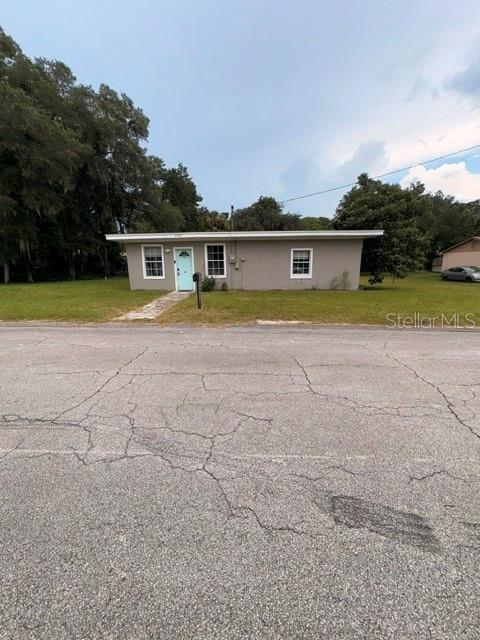A single-story house with a flat roof, light-colored door, and gray exterior siding — 5025 PENVAN AVENUE, DE LEON SPRINGS, FL