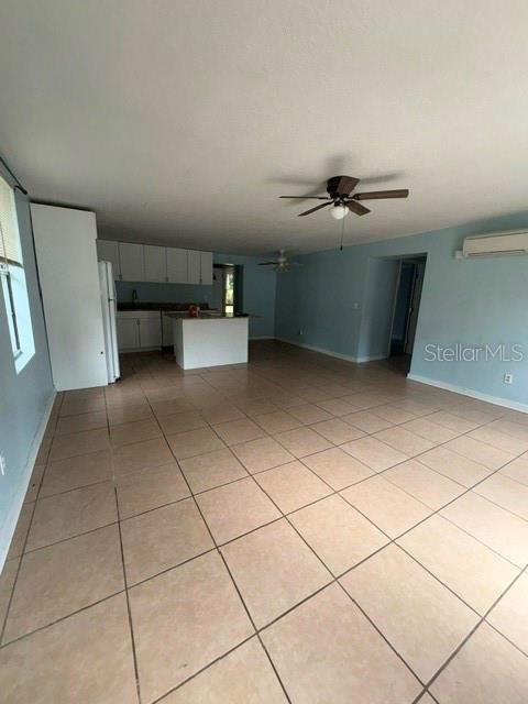 A spacious room with light-colored tile flooring, a ceiling fan, and an open kitchen area — 5025 PENVAN AVENUE, DE LEON SPRINGS, FL