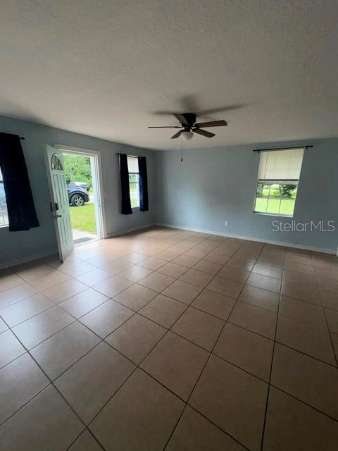 A living room with light blue walls, tan tile flooring, and a ceiling fan — 5025 PENVAN AVENUE, DE LEON SPRINGS, FL