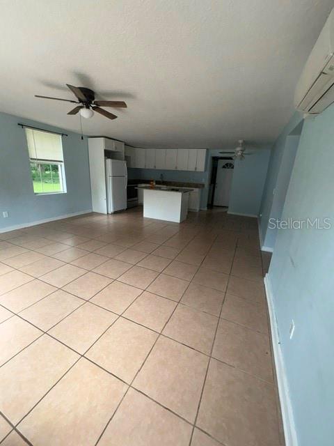 An open-concept kitchen and living area features light blue walls and tan tile flooring — 5025 PENVAN AVENUE, DE LEON SPRINGS, FL
