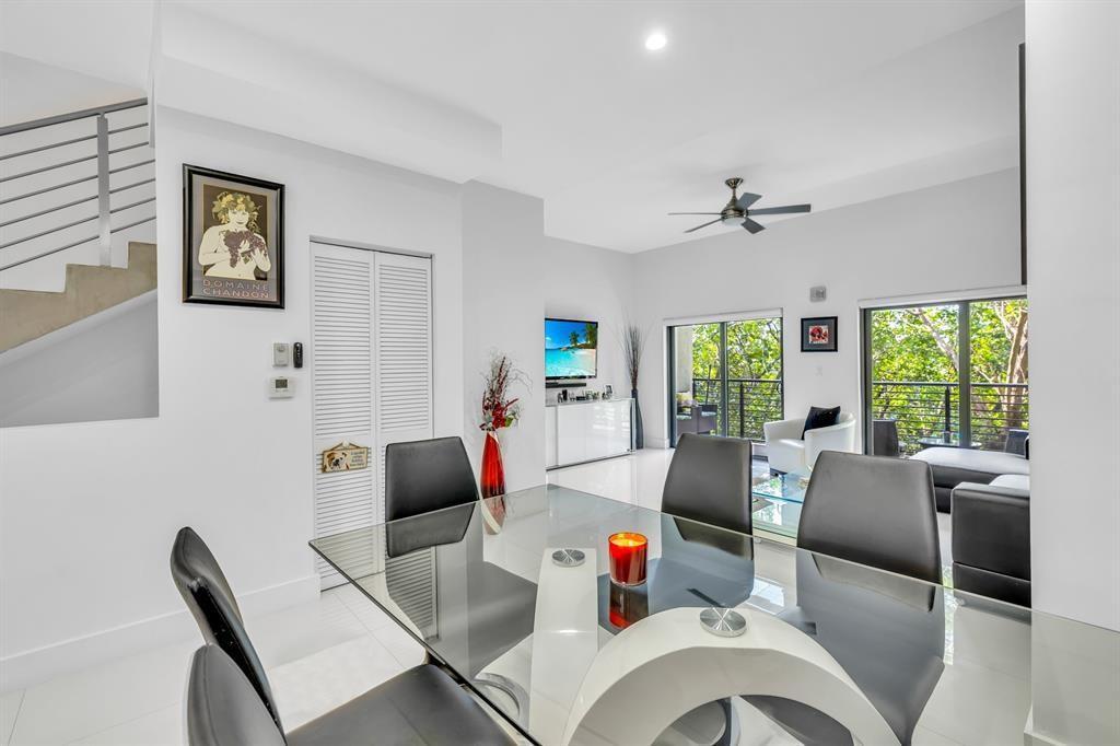 A modern dining room features a glass table, black chairs, and large sliding glass doors — 462 SE 1st Circle, Pompano Beach FL 33060, POMPANO BEACH, FL