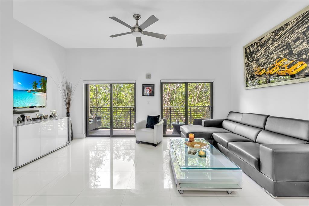 A modern living room features white tile floors, a black leather sectional, and glass doors — 462 SE 1st Circle, Pompano Beach FL 33060, POMPANO BEACH, FL