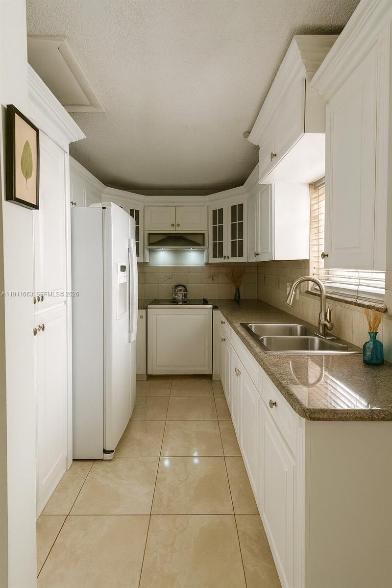 A galley kitchen features white cabinets, granite countertops, a double sink, and tile flooring — 1101 SW 17 AVE, Miami FL 33135, MIAMI, FL