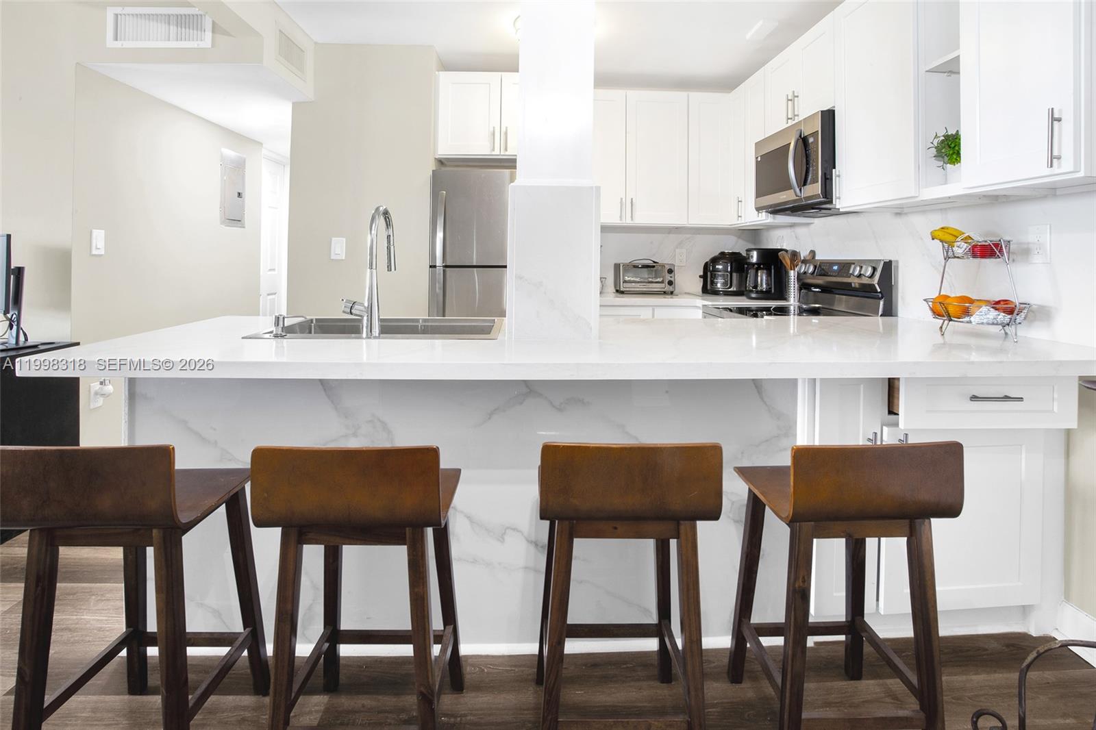 An open-concept living area features a kitchen with bar seating, wood flooring, and a balcony — 9682 Fontainebleau Blvd # 503, Miami FL 33172, MIAMI, FL