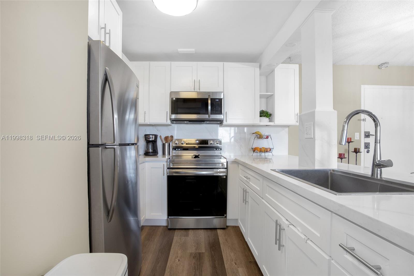 A kitchen features white cabinets, stainless steel appliances, and a white marble-look countertop island — 9682 Fontainebleau Blvd # 503, Miami FL 33172, MIAMI, FL