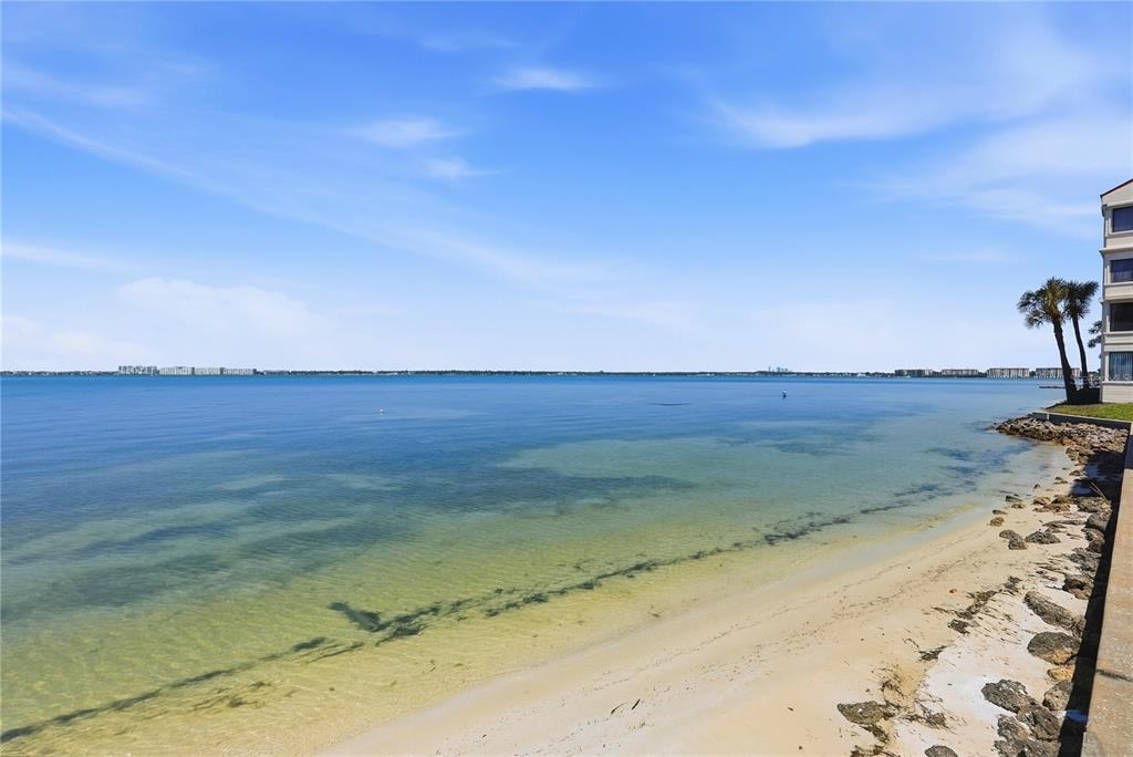 A view of a sandy beach and calm water next to a multi-story building — 5729 PUERTA DEL SOL BOULEVARD S UNIT 181, ST PETERSBURG, FL