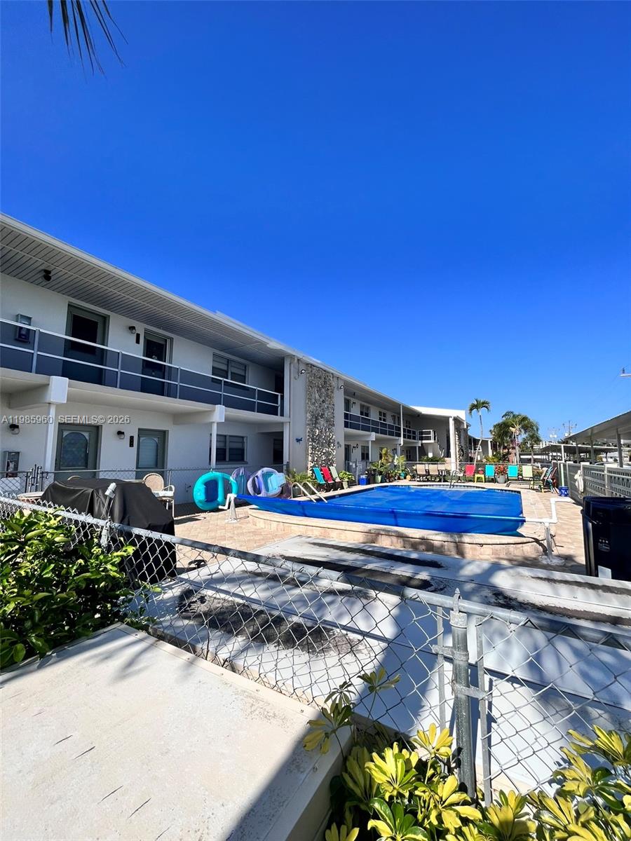 A two-story apartment building features a swimming pool with a blue cover in the courtyard — 708 Victoria Dr # 101, Cape Coral FL 33904, CAPE CORAL, FL