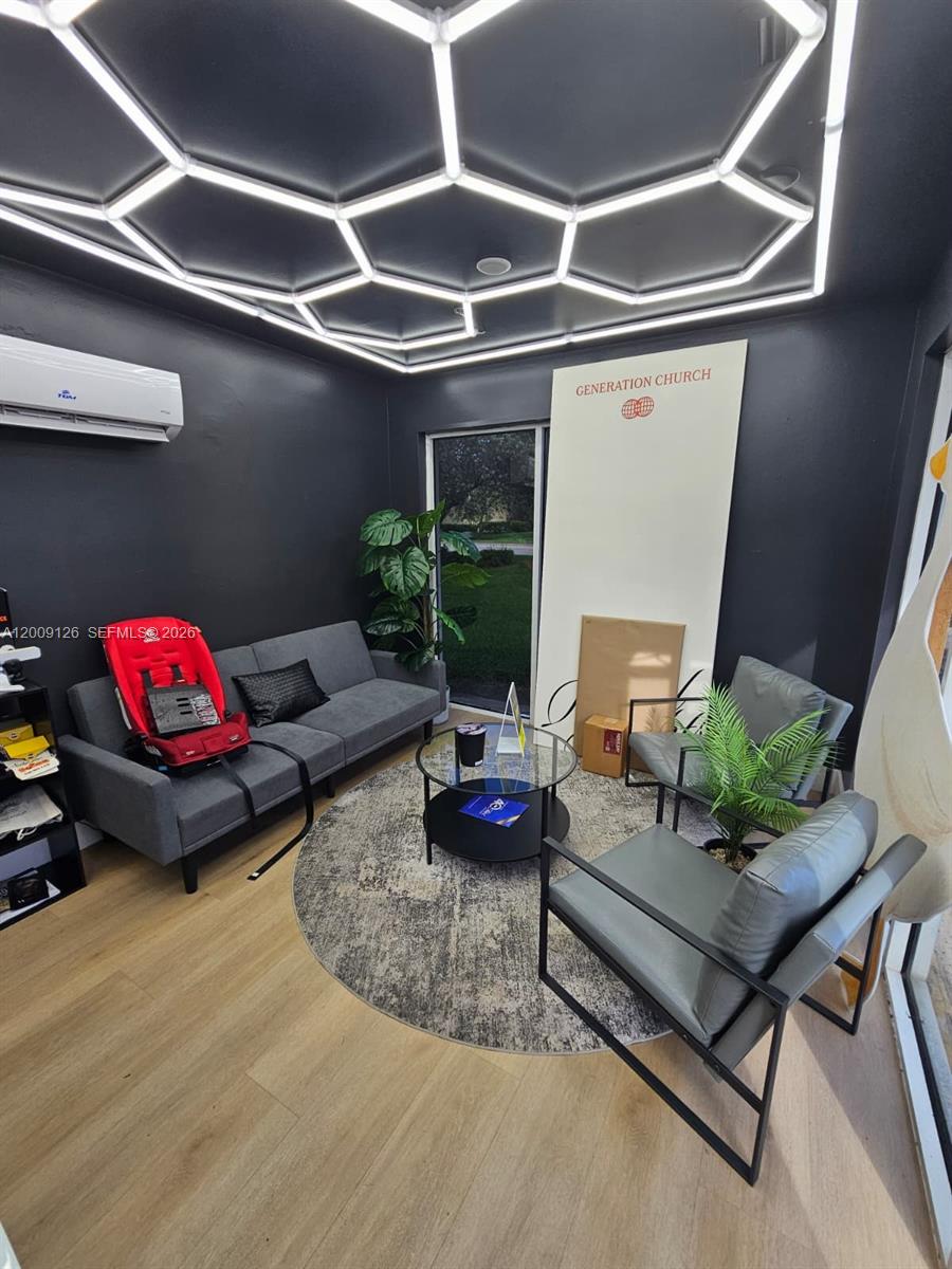 A modern lounge area features a hexagonal LED ceiling, dark walls, and gray seating furniture — 13850 SW 143rd Ct # 14, Miami FL 33186, MIAMI, FL