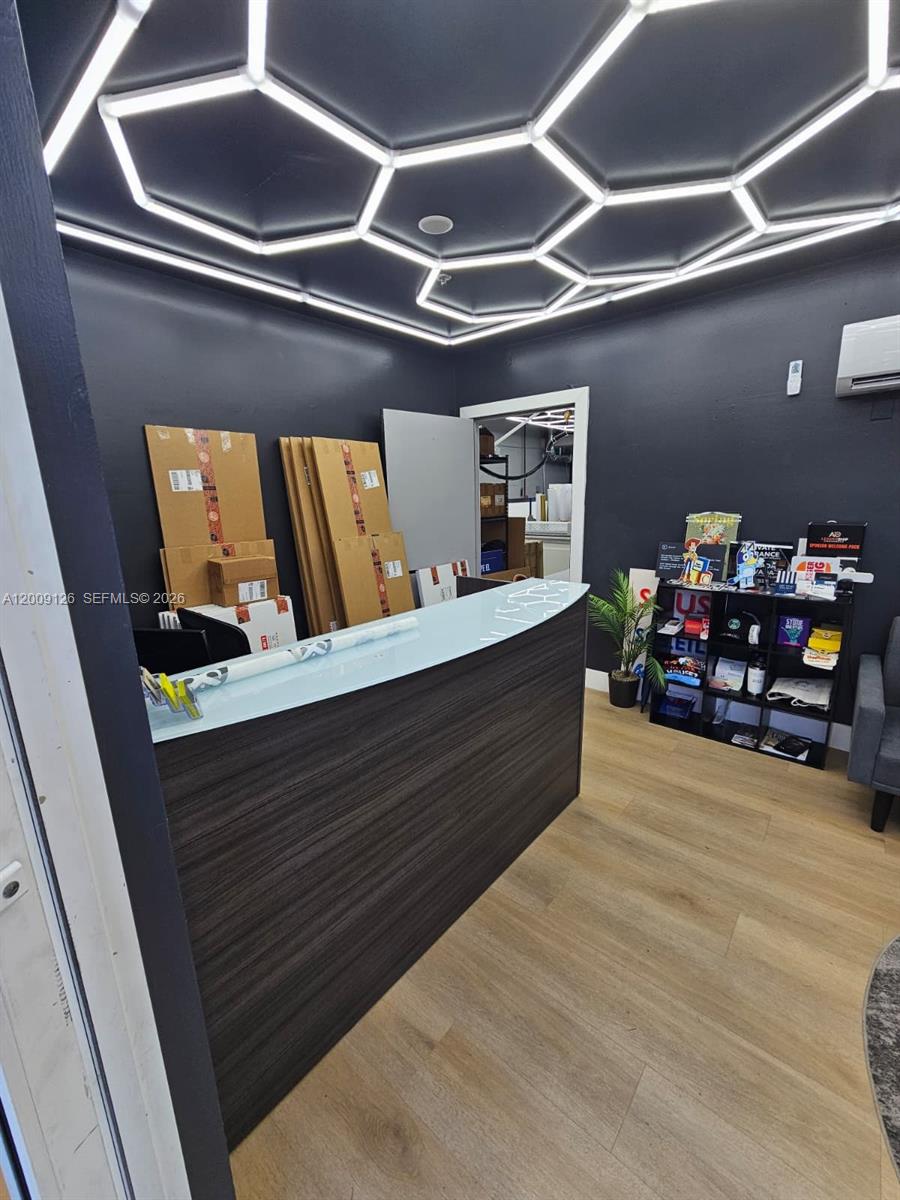 A reception area features a dark wood desk, light wood flooring, and a geometric ceiling light — 13850 SW 143rd Ct # 14, Miami FL 33186, MIAMI, FL