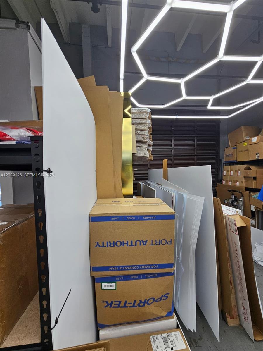 A storage area contains stacked cardboard boxes, large white panels, and modern geometric ceiling lights — 13850 SW 143rd Ct # 14, Miami FL 33186, MIAMI, FL