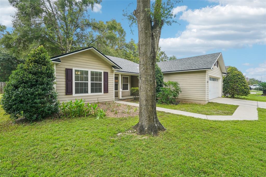 A single-story house with tan siding, a two-car garage, and a front walkway — 12104 NW 162ND DRIVE, ALACHUA, FL