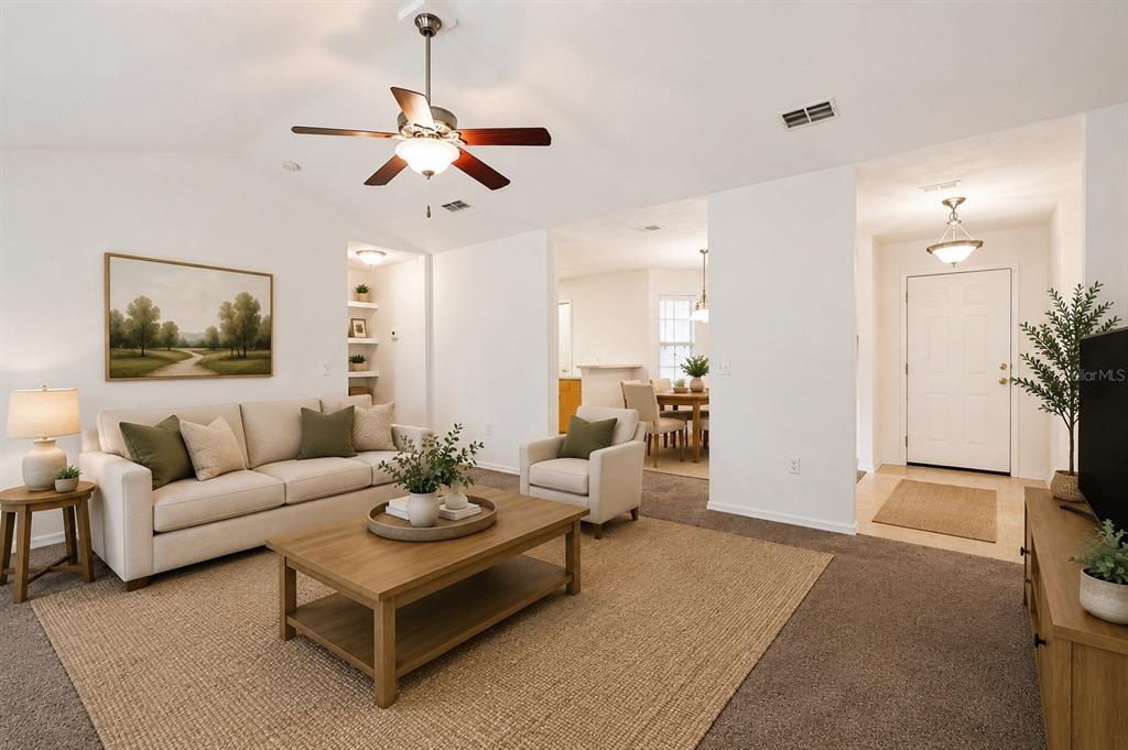 A living room with a beige sofa, wooden coffee table, and an adjacent dining area — 12104 NW 162ND DRIVE, ALACHUA, FL