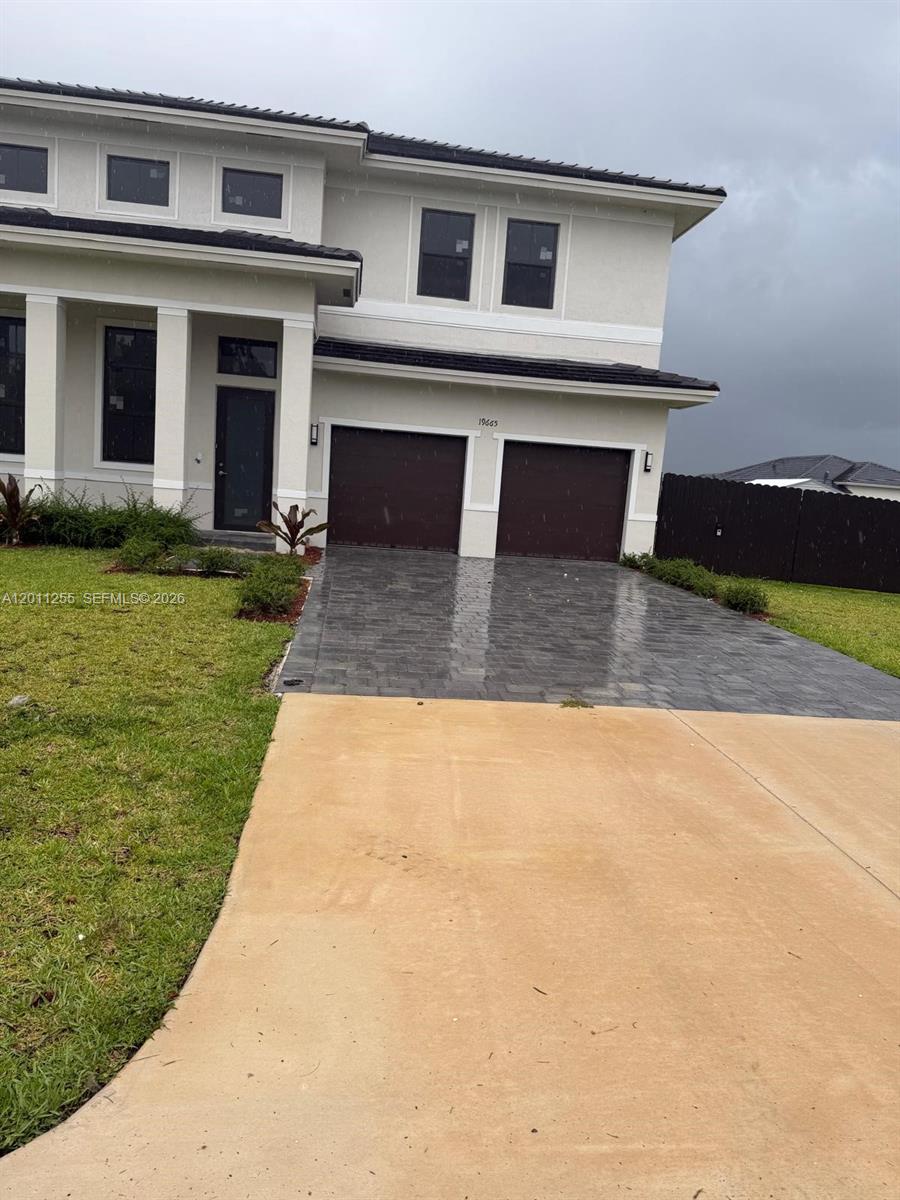 A two-story house features a paved driveway, two garage doors, and a light-colored exterior — HOMESTEAD, FL