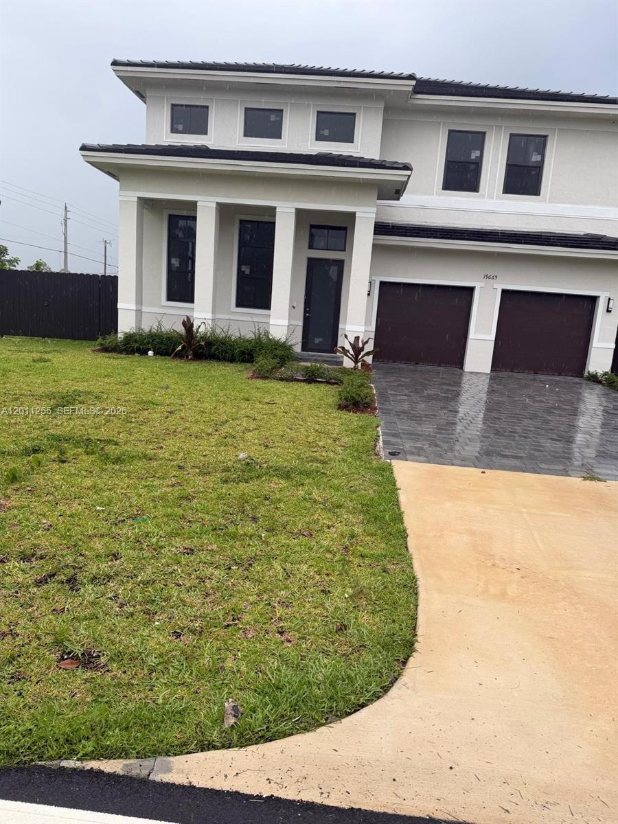 A two-story house with a white exterior, dark garage doors, and a paved driveway — HOMESTEAD, FL
