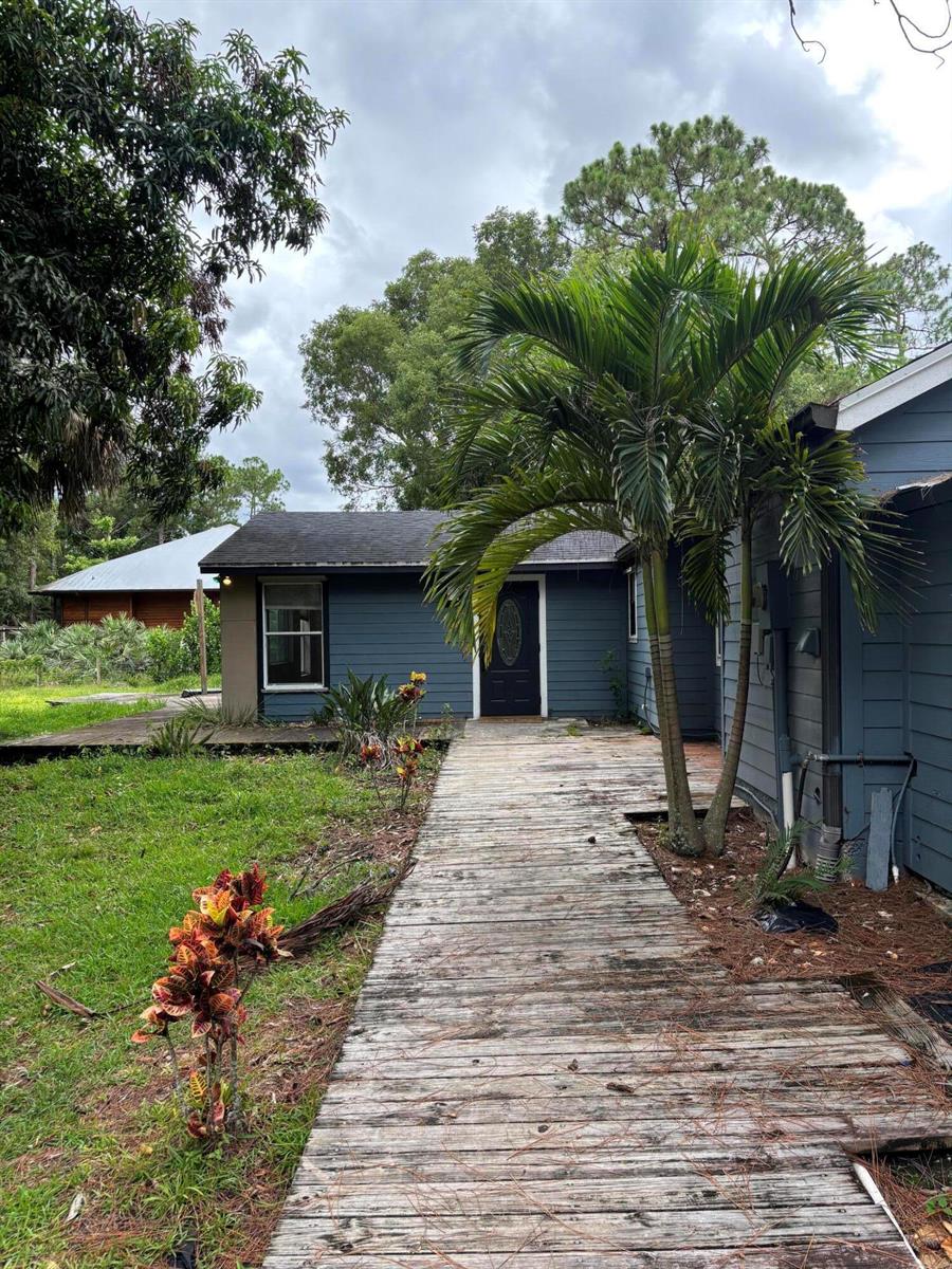 A blue house with a wooden walkway leading to the front door and palm trees — 11656 N 154th Rd Road N, FL 33478, FL
