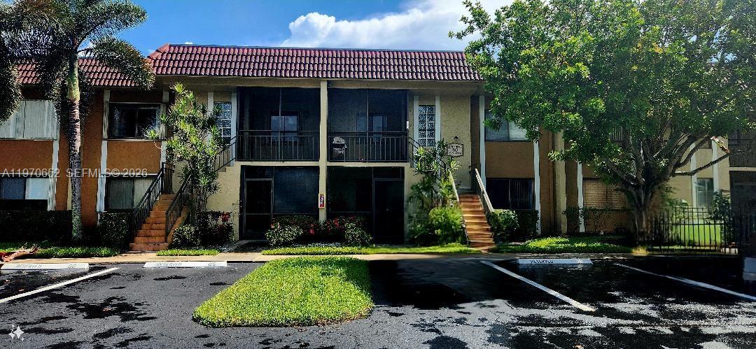 A two-story apartment building features screened balconies, a tiled roof, and a parking lot — 327 Lakeview Dr # 103, Weston FL 33326, WESTON, FL