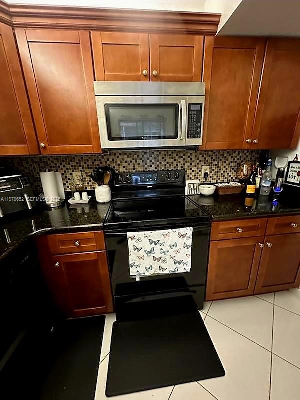 A kitchen features wooden cabinets, a stainless steel microwave, and a black electric stove — 327 Lakeview Dr # 103, Weston FL 33326, WESTON, FL