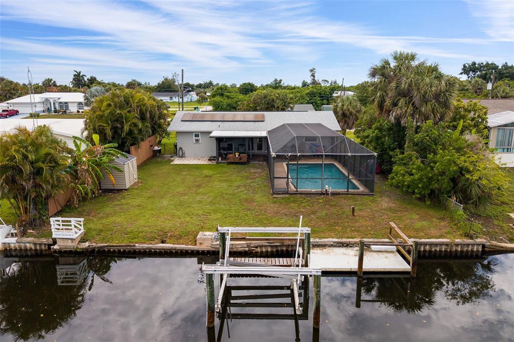 An aerial view shows a house with a pool enclosure, backyard, and a private boat lift — 3601 WISTERIA PLACE, PUNTA GORDA, FL
