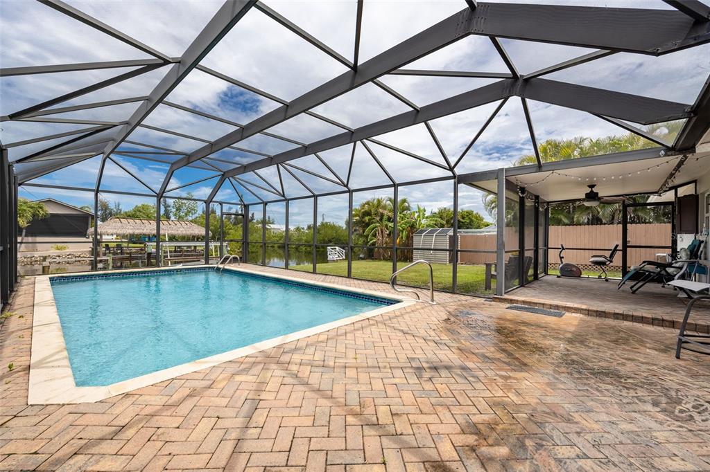 A screened-in pool patio features brick pavers, a rectangular swimming pool, and a covered area — 3601 WISTERIA PLACE, PUNTA GORDA, FL