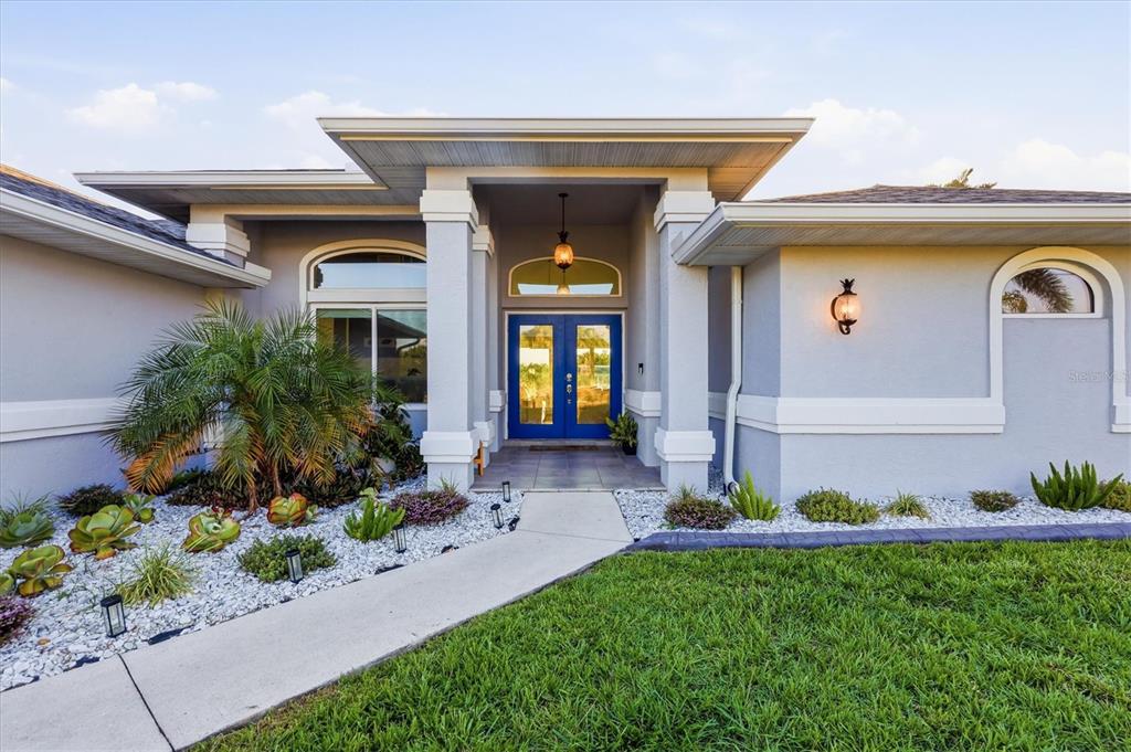 A light blue house exterior features a covered entryway with bright blue double front doors — 430 SPRING LAKE BOULEVARD NW, PORT CHARLOTTE, FL