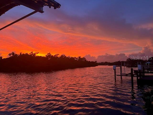 A vibrant sunset glows over a calm waterway with a wooden dock in the foreground — 430 SPRING LAKE BOULEVARD NW, PORT CHARLOTTE, FL
