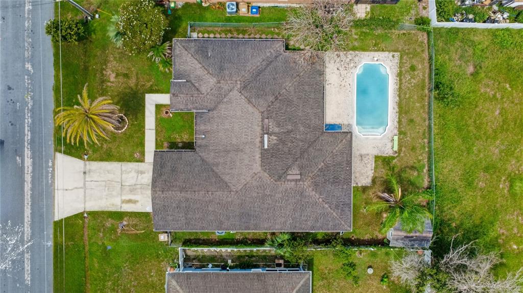 An aerial view shows a house with a shingled roof, a swimming pool, and landscaping — 121 AURELIA COURT, KISSIMMEE, FL