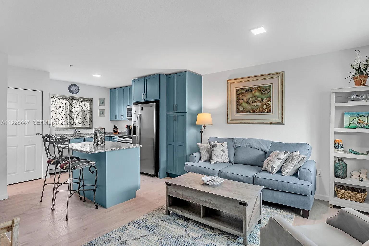 A living room and kitchen area feature blue cabinets, a blue sofa, and light wood flooring — 10877 Overseas Hwy # 37, Marathon FL 33050, MARATHON, FL