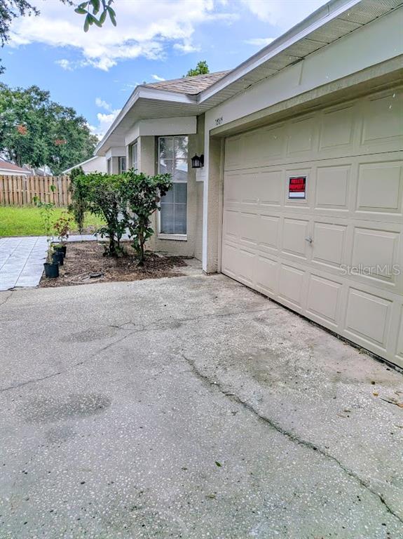 A concrete driveway leads to a beige garage door and a house exterior with landscaping — 7885 CAMLYN COURT, ORLANDO, FL