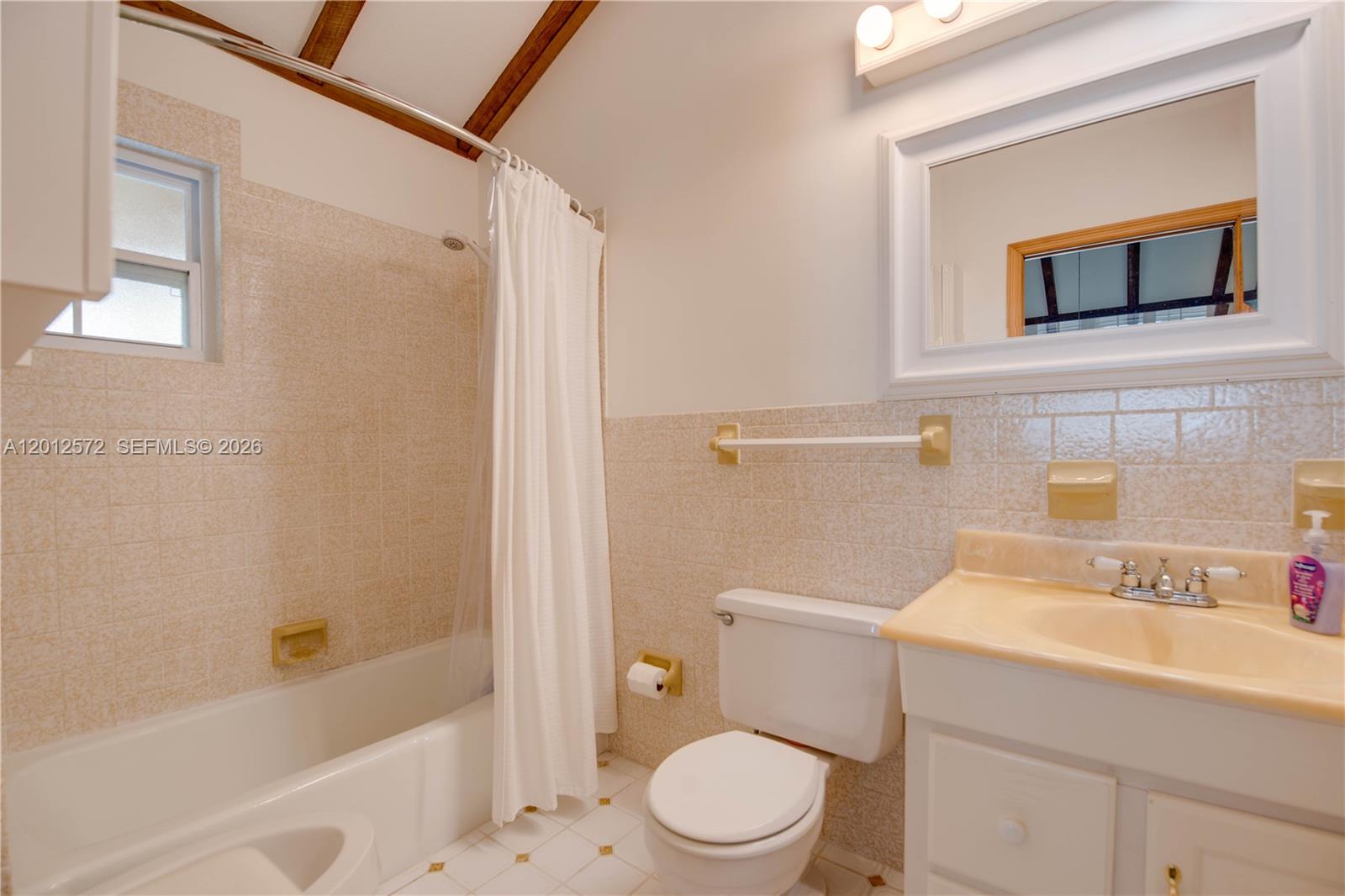 A bathroom features a white tub, a toilet, a vanity, and beige tiled walls — 29662 Independence Ave, Big Pine FL 33043, BIG PINE, FL