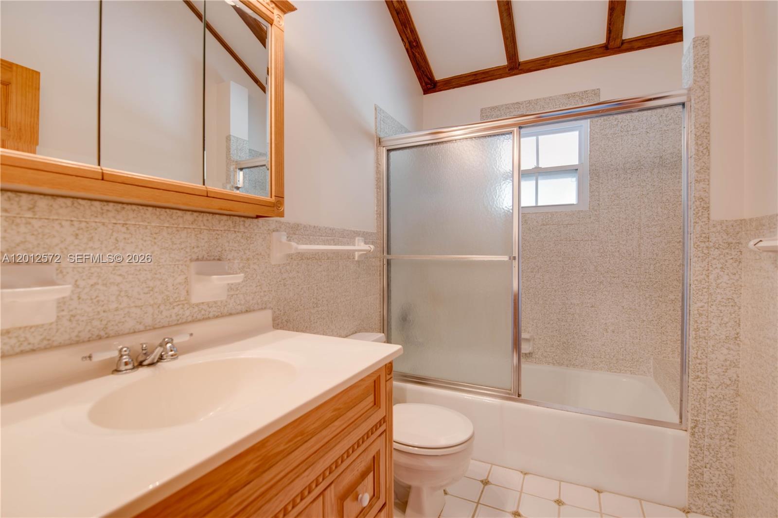 A bathroom features a wooden vanity, a mirrored medicine cabinet, and a shower-tub combination — 29662 Independence Ave, Big Pine FL 33043, BIG PINE, FL