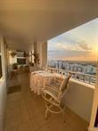 A balcony with a small table and chairs overlooks a city skyline at sunset — 1340 S Ocean Boulevard # 1509, Pompano Beach FL 33062, POMPANO BEACH, FL