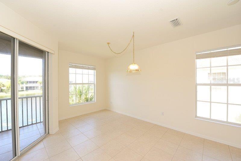 This dining area features tile flooring, a hanging light fixture, and sliding glass balcony doors — 7106 PROSPERITY CIRCLE UNIT 1201, SARASOTA, FL